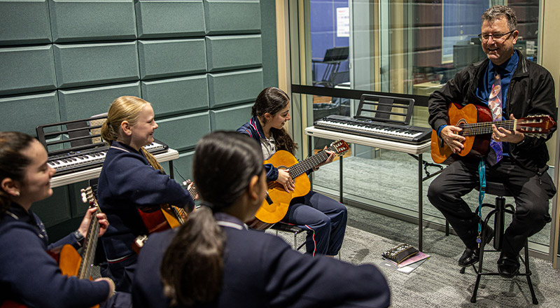 Santa Sophia Catholic College Box Hill dedicated teacher and students learning guitar