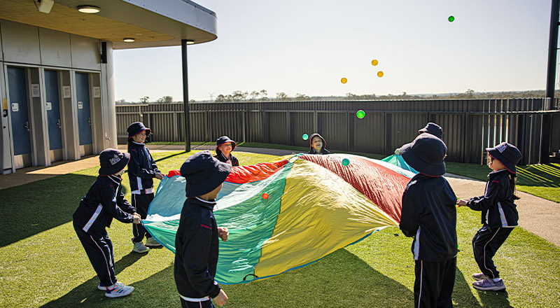Santa Sophia Catholic College Box Hill students playing with a rainbow parachute