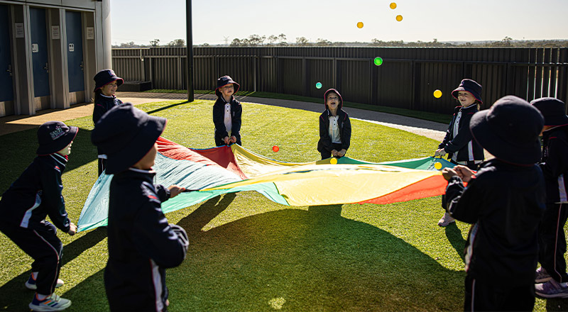 Santa Sophia Catholic College Box Hill students playing with a rainbow parachute